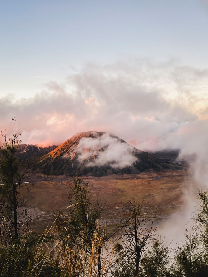 ruta por indonesia monte bromo volcan entre nubes al amanecer con tonos rosados